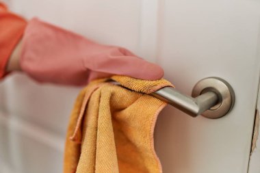 Orta yaşlı kadın gülümseyerek evde temizlik yapıyor..