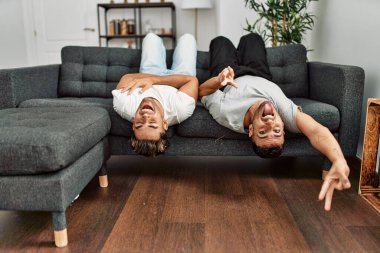 İki İspanyol erkek, evdeki kanepede yatıp gülümsüyor.