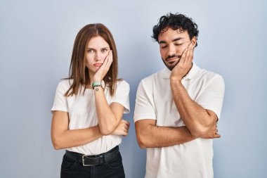 Young couple wearing casual clothes standing together thinking looking tired and bored with depression problems with crossed arms. 