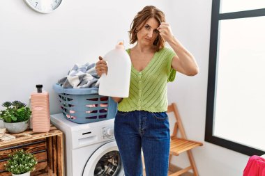 Orta yaşlı bir kadın çamaşır deterjanı şişesini tutuyor öfkeyle bağırıyor, öfkeyle bağırıyor ve el kaldırıyor. 