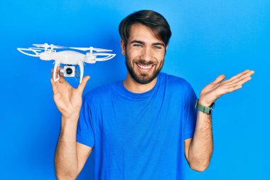 İspanyol asıllı genç adam başarıyı kutlamak için İHA 'yı tutarken mutlu bir gülümseme ve elini kaldırarak kazanan bir ifade takındı. 