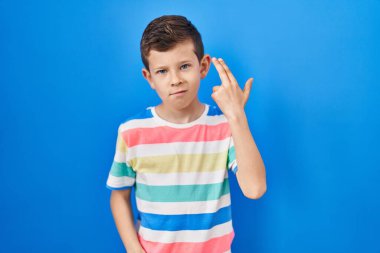 Kafkasyalı genç, mavi arka planda durup ateş ederek kendini ve parmaklarını silah gibi işaret ederek öldürüyor, intihar jesti.. 