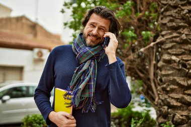 Orta yaşlı yakışıklı adam parkta dışarıda telefonla konuşuyor.