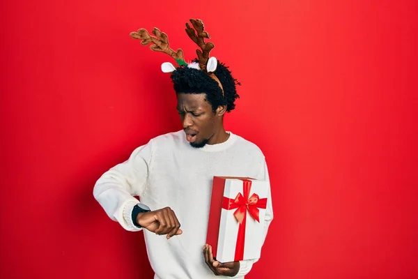 Jovem Afro Americano Usando Chapéu Natal Veado Segurando Presente Olhando — Fotografia de Stock