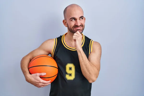 年轻的秃头男子 留着胡子 身穿篮球服 手托着下巴思考着问题 沉思着表情 微笑和体贴的脸 怀疑概念 — 图库照片