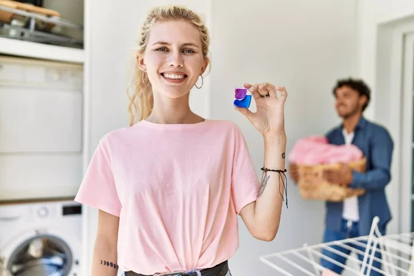 Pareja Joven Lavando Ropa Mujer Sonriendo Feliz Sosteniendo Detergente Casa —  Fotos de Stock