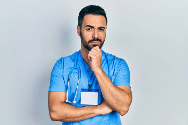 Hombre Hispano Guapo Con Barba Vistiendo Uniforme Médico Cara Seria —  Fotos de Stock