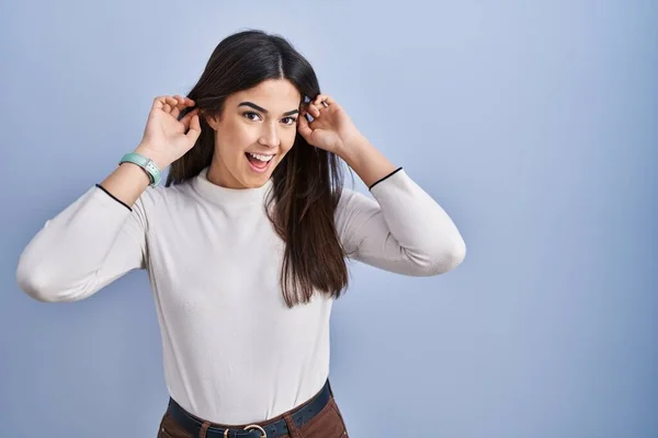 Jonge Brunette Vrouw Staat Blauwe Achtergrond Glimlachende Trekkende Oren Met — Stockfoto