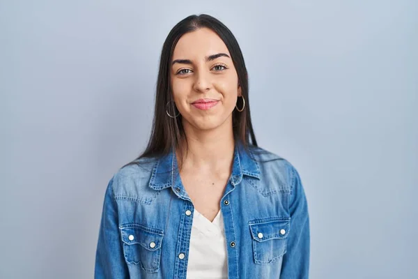 Hispanic woman standing over blue background relaxed with serious expression on face. simple and natural looking at the camera.