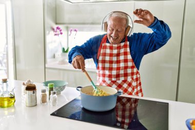 Son sınıf öğrencisi mutfakta spagetti pişirirken müzik dinliyor.