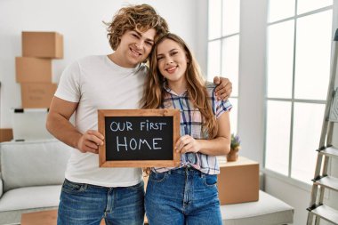 Kafkasyalı genç çift yeni evimizin tahtasını tutuyor. Yeni evimizde birbirlerine sarılıyorlar.