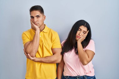 Tecrit edilmiş arka planda duran genç çift çapraz kollu depresyon sorunlarından yorgun ve sıkılmış göründüklerini düşünüyor.. 