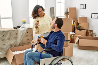 Orta yaşlı İspanyol çift şampanyayla kadeh kaldırıyor. Tekerlekli sandalyede oturan bir adam ve yeni evinde ayakları üzerinde duran bir köpek.