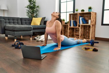 Young woman having online stretching class at home