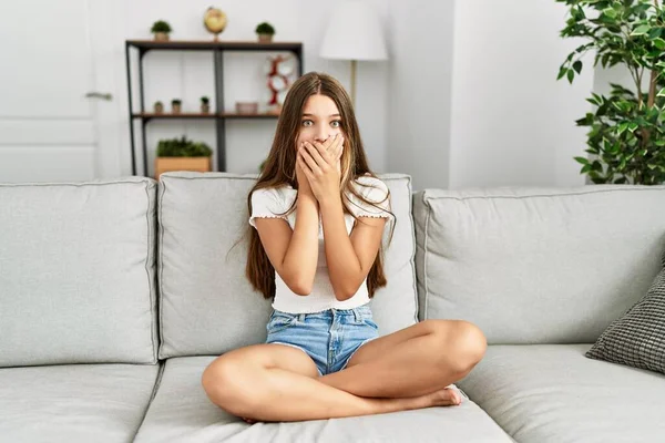 Young Brunette Teenager Sitting Sofa Home Shocked Covering Mouth Hands — Stockfoto