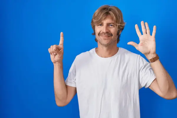 Middelbare Leeftijd Man Staande Blauwe Achtergrond Tonen Wijzen Met Vingers — Stockfoto