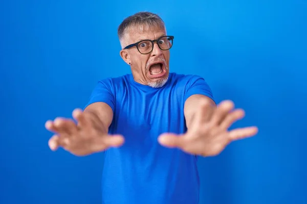 Homem Hispânico Com Cabelos Grisalhos Sobre Fundo Azul Com Medo — Fotografia de Stock