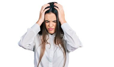 Young brunette teenager wearing business white shirt suffering from headache desperate and stressed because pain and migraine. hands on head. 