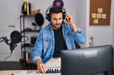 Young hispanic man singing song at music studio