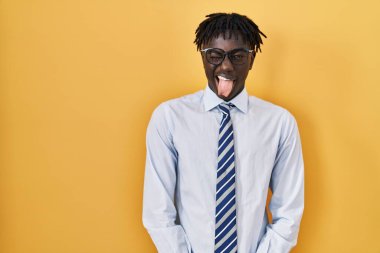 Sarı arka planda duran Afrikalı adam komik bir ifadeyle dilini dışarı çıkartıyor. duygu kavramı. 