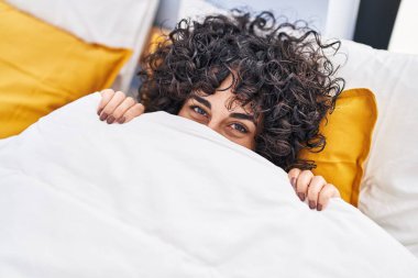 Orta Doğulu genç bir kadın yatak odasında ağzını kapatıyor.