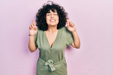 Orta Doğulu genç bir kadın günlük kıyafetler giyip umut ve gözlerin kapalı gülümseyerek el sallıyor. Şans ve batıl inançlar. 