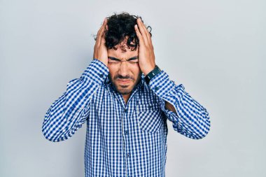 İspanyol asıllı genç adam gündelik giysiler giyiyor. Baş ağrısı çekiyor. Acı ve migren yüzünden çaresiz ve stresli. Eller başının üstünde.. 