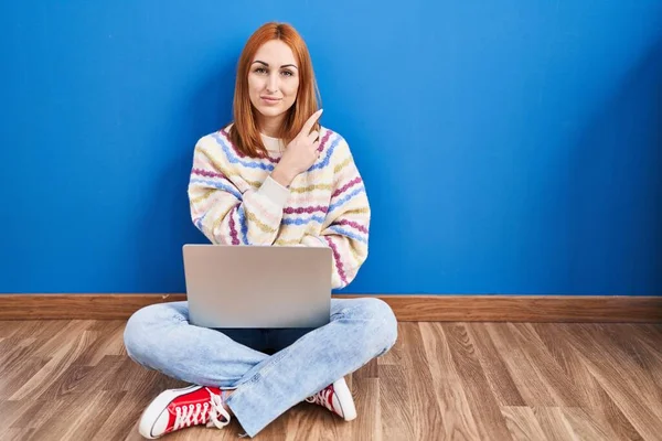 Молода Жінка Використовуючи Ноутбук Вдома Сидить Підлозі Вказуючи Пальцем Бік — стокове фото