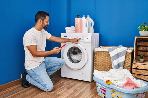 Jonge Spaanse Man Zet Wasmachine Met Behulp Van Smartphone Wasruimte — Stockfoto