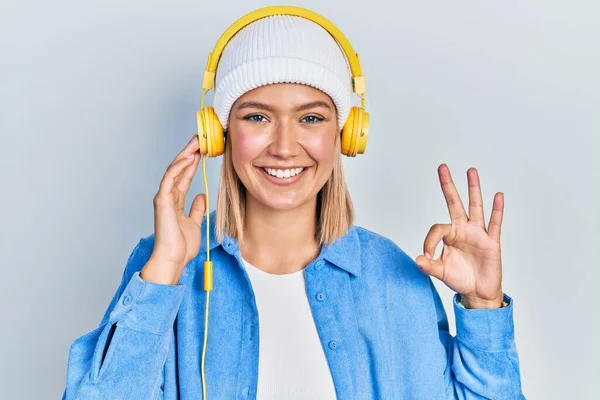 Beautiful Blonde Woman Listening Music Using Headphones Doing Sign Fingers — Stock fotografie