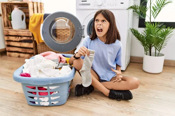 Young Hispanic Girl Doing Laundry Holding Socks Angry Mad Screaming — ストック写真