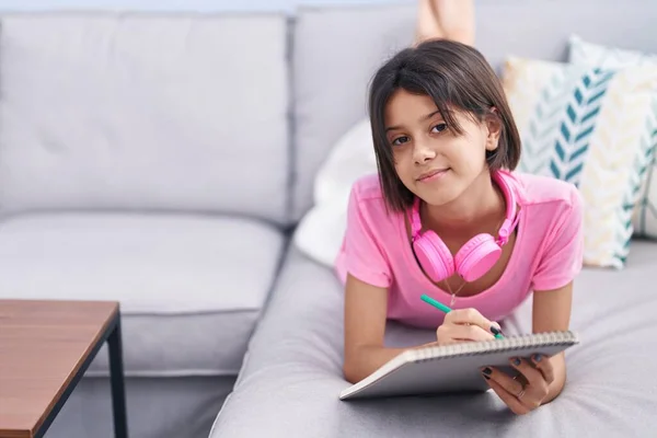 Adorable Hispanic Girl Writing Notebook Lying Sofa Home — Stok fotoğraf