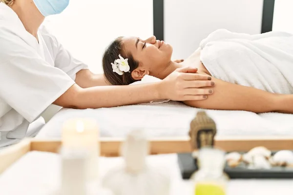 Young latin woman relaxed having shoulders massage at beauty center