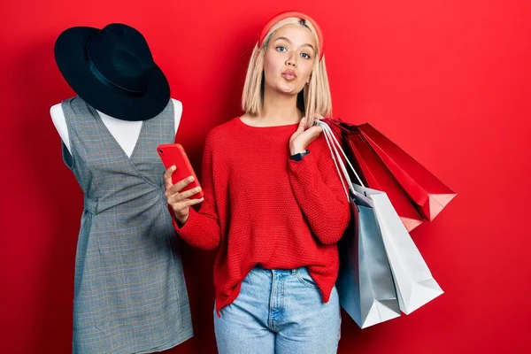 Beautiful Blonde Woman Holding Shopping Bags Smartphone Looking Camera Blowing — 图库照片