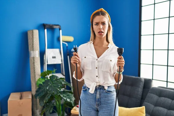 Young Blonde Woman Moving New Home Holding Plugs Clueless Confused — 스톡 사진