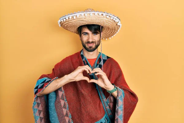 Young Hispanic Man Holding Mexican Hat Smiling Love Doing Heart — Fotografia de Stock