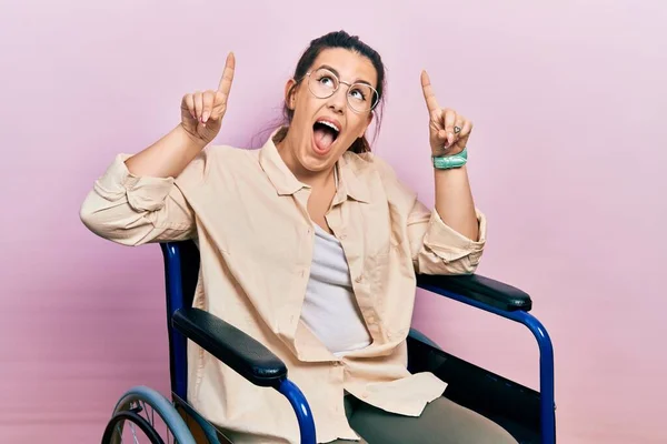 Young Hispanic Woman Sitting Wheelchair Smiling Amazed Surprised Pointing Fingers — Photo