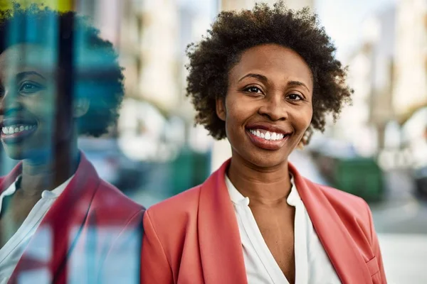 Beautiful business african american woman with afro hair smiling happy and confident outdoors at the city