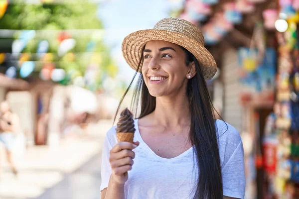 Young hispanic woman tourist smiling confident eating ice cream at street market