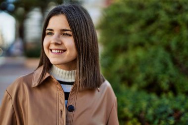 Genç, güzel, esmer kadın dışarıda mutlu bir şekilde gülümsüyor.