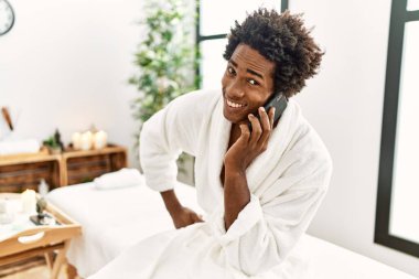 Genç Afrikalı Amerikalı gülümseyen, kendine güvenen güzellik merkezinde akıllı telefondan konuşan.