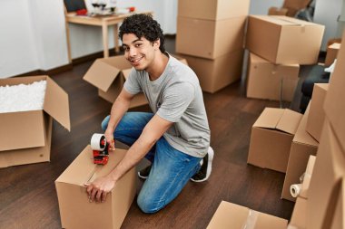 Genç İspanyol adam gülümsüyor yeni evinde mutlu bir paket kutusu var..