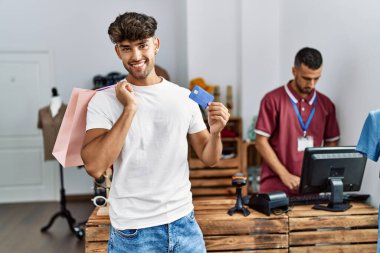 Genç İspanyol müşteri alışveriş çantası ve kredi kartını giyim mağazasında tutuyor..