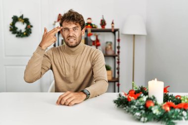 Genç, sakallı yakışıklı adam Noel süslemeleri ile masada oturuyor. Silah gibi el ve parmakları göstererek ateş ediyor ve kendini öldürüyor. İntihar jesti.. 