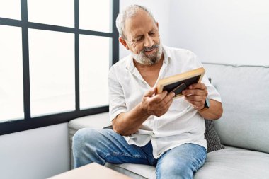 Yaşlı, gri saçlı, gülümseyen, kendine güvenen bir adam.