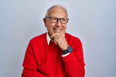 Senior man with grey hair standing over isolated background with hand on chin thinking about question, pensive expression. smiling and thoughtful face. doubt concept. 