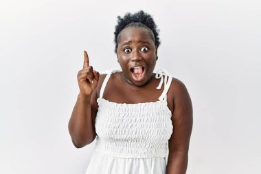 Genç Afrikalı bir kadın izole edilmiş beyaz arka planda durup başarılı bir fikir işaret ediyor. Heyecanlı ve mutlu. Bir numara.. 