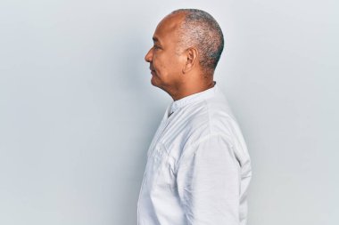 Orta yaşlı, sıradan kıyafetler giyen, rahat bir görünüm takınan, kendine güvenen gülümseyen Latin bir adam.. 