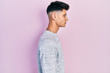 Latin kökenli genç adam rahat bir görünüm takınıyor, rahat bir görünüm takınıyor, kendine güvenen bir gülümsemeyle.. 