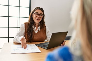 Ofiste çalışırken gülümseyen iki iş kadını..